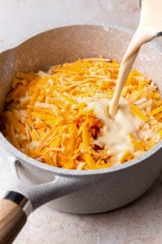 pouring cream into a pot of shredded cheese