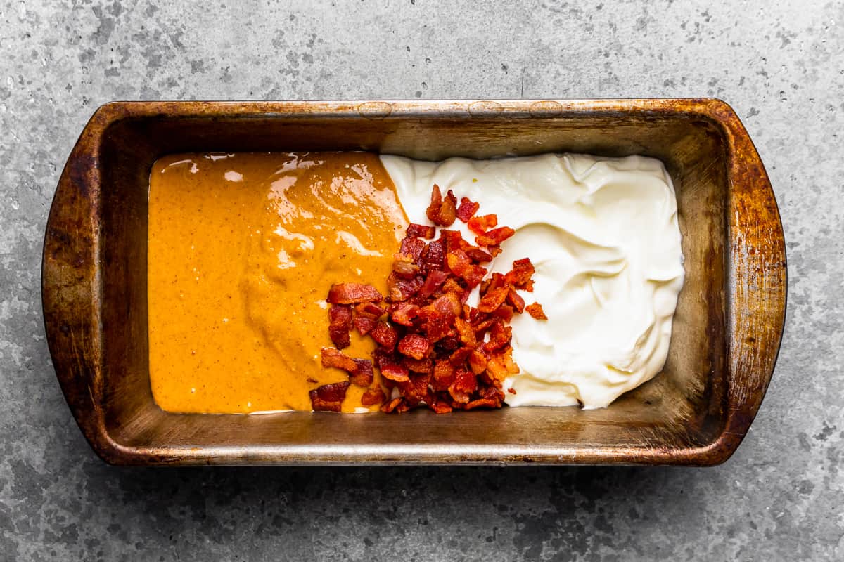 Rustic metal pan filled with peanut butter, yogurt, and bacon bits.