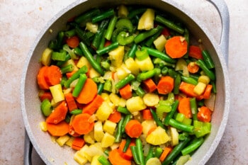 large pot filled with chopped up carrots, potatoes, green beans