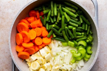large pot with chopped green beans, celery, carrots, and parsnpis, separated into separate sections