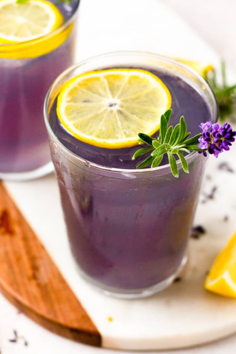 glass of lavender lemonade with a slice of lemon and lavender as garnish