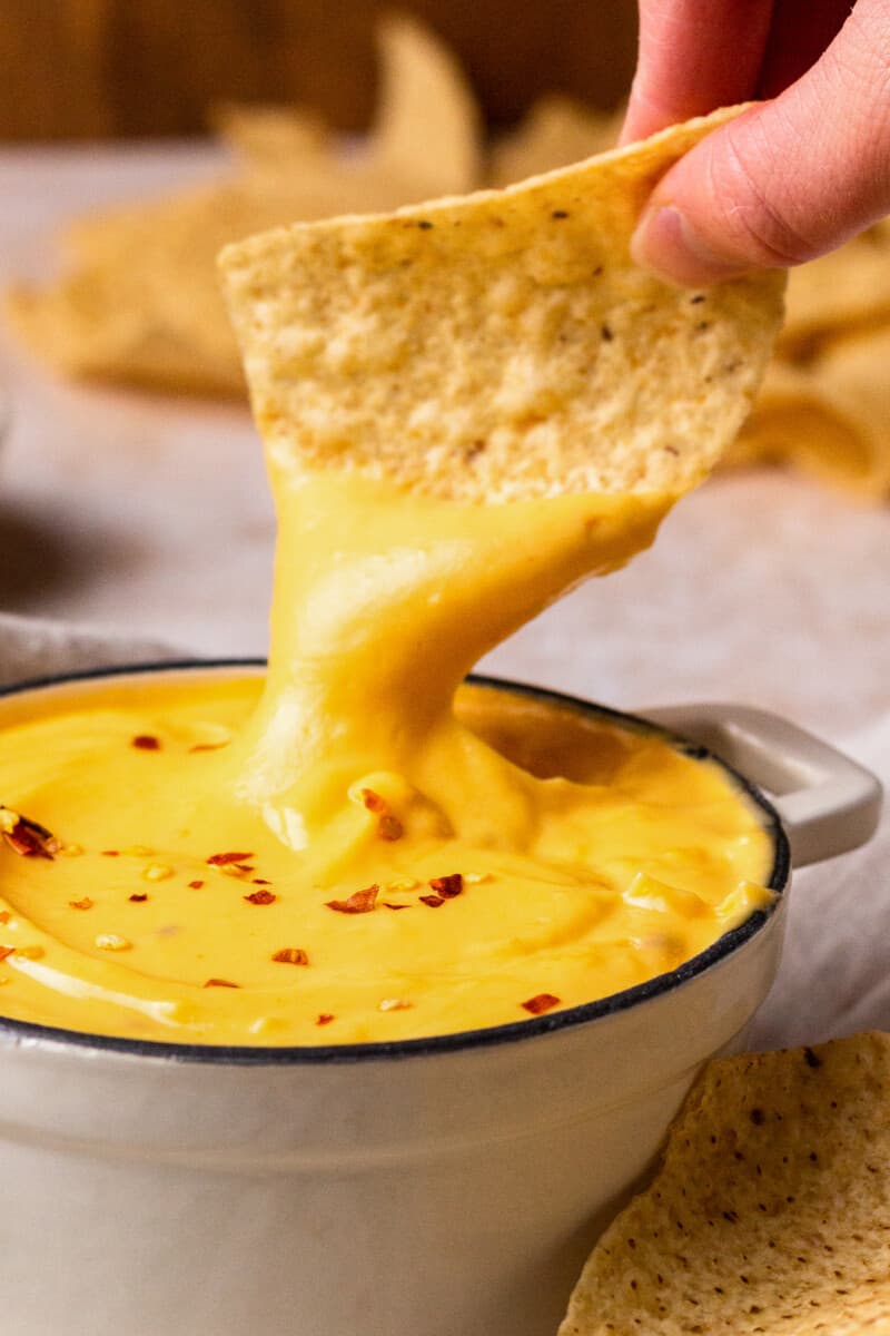 dipping a tortilla chip into nacho cheese dip