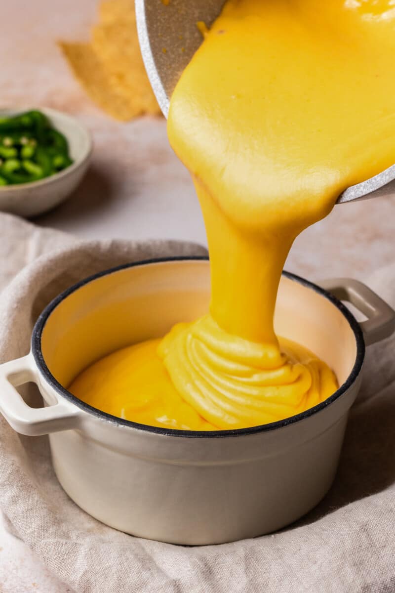 pouring nacho cheese sauce into a bowl