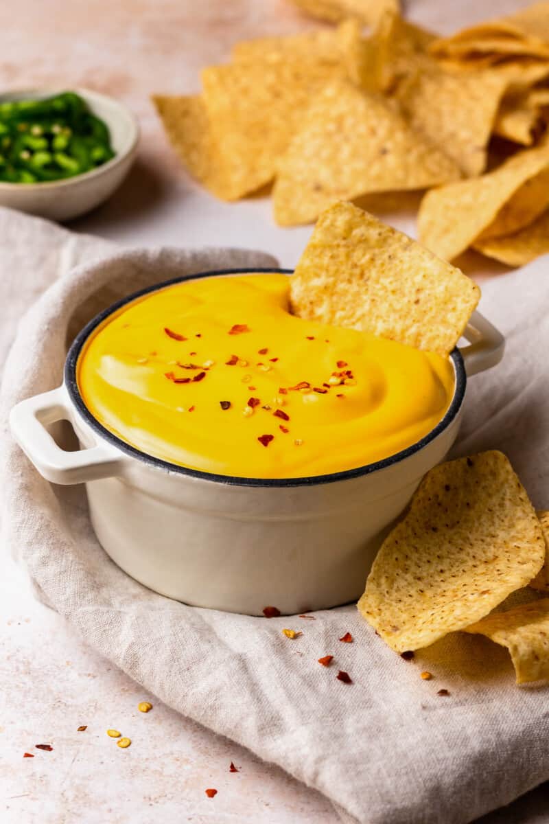 bowl of nacho cheese with tortilla chips dipped in it