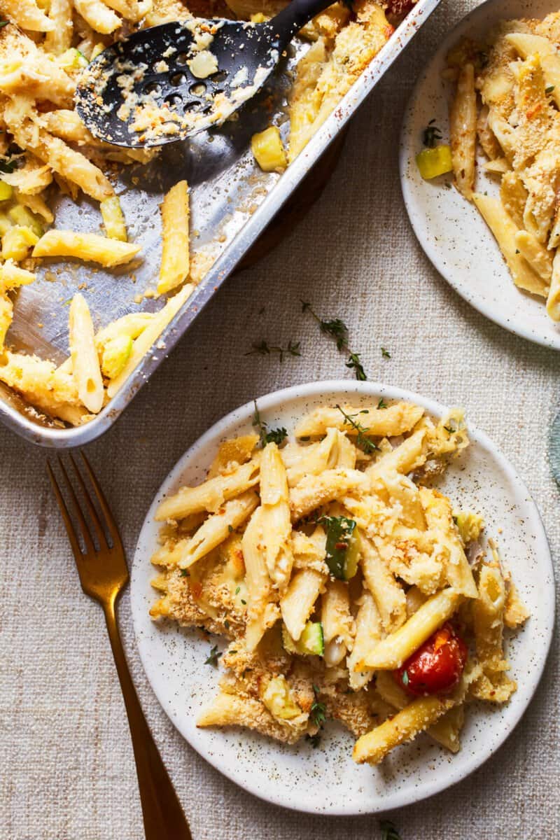 a plate of baked pasta primavera next to a baking dish fill of pasta