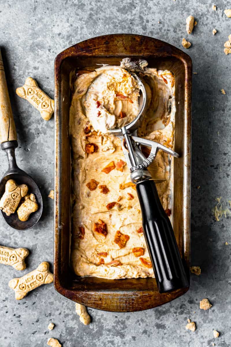 rustic metal pan filled with homemade dog ice cream, with an ice cream scoop laying on top