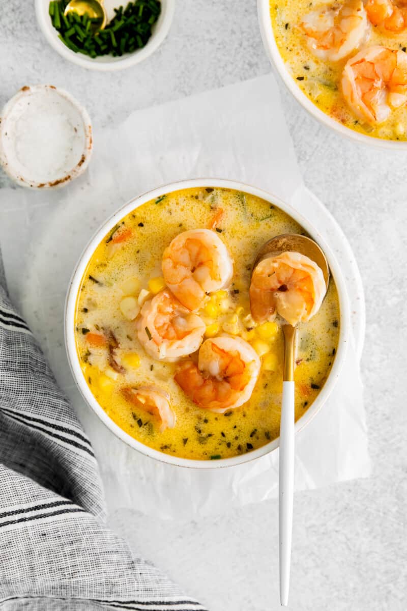 shrimp corn chowder in a white bowl with a spoon.