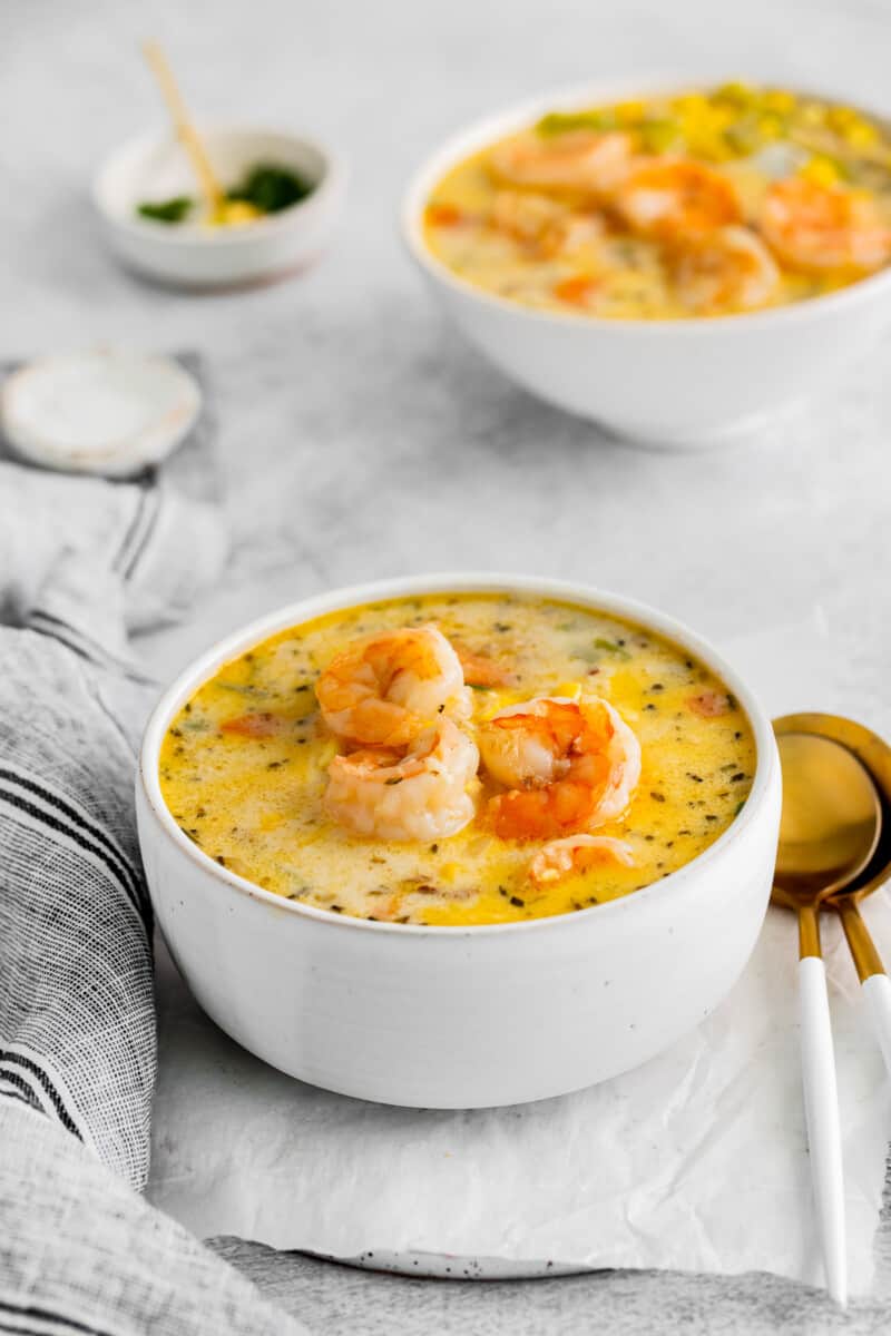 shrimp corn chowder in a white bowl with spoons.