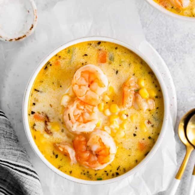shrimp corn chowder in a white bowl with spoons.