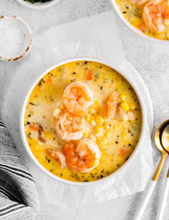 shrimp corn chowder in a white bowl with spoons.