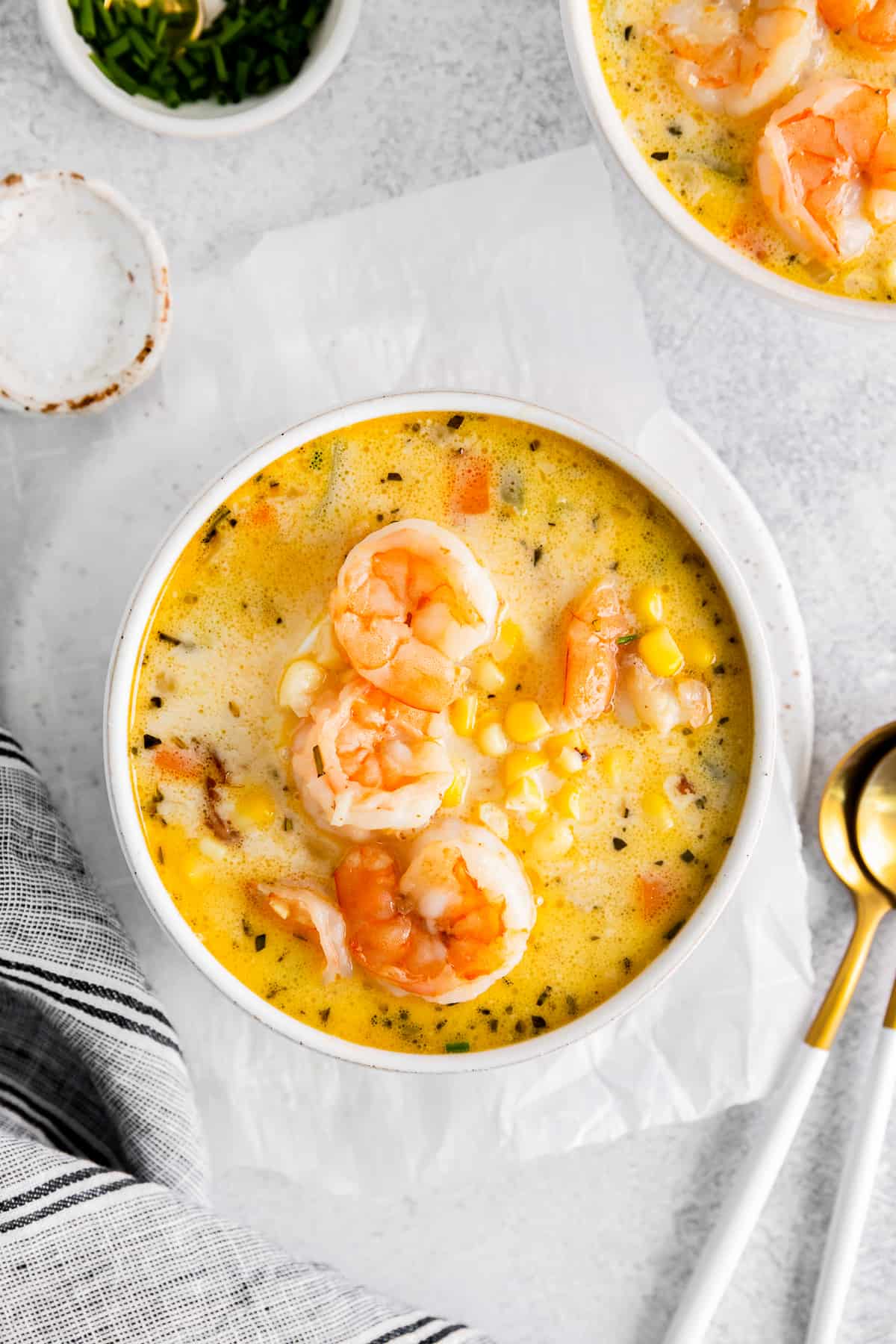 shrimp corn chowder in a white bowl with spoons.