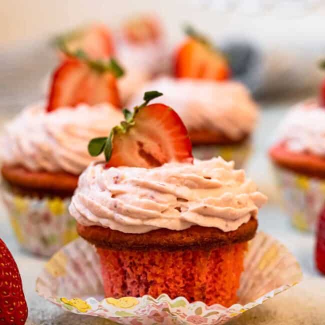 unwrapped strawberry cupcake on a colorful cupcake wrapper.