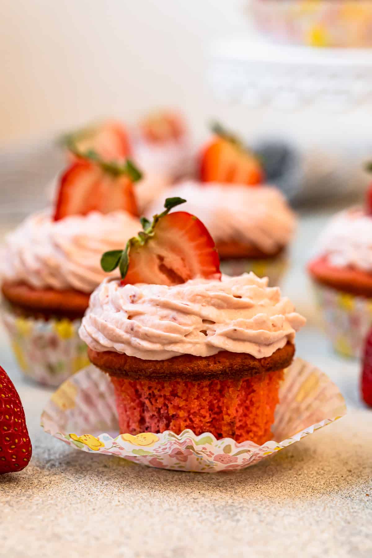 unwrapped strawberry cupcake on a colorful cupcake wrapper.