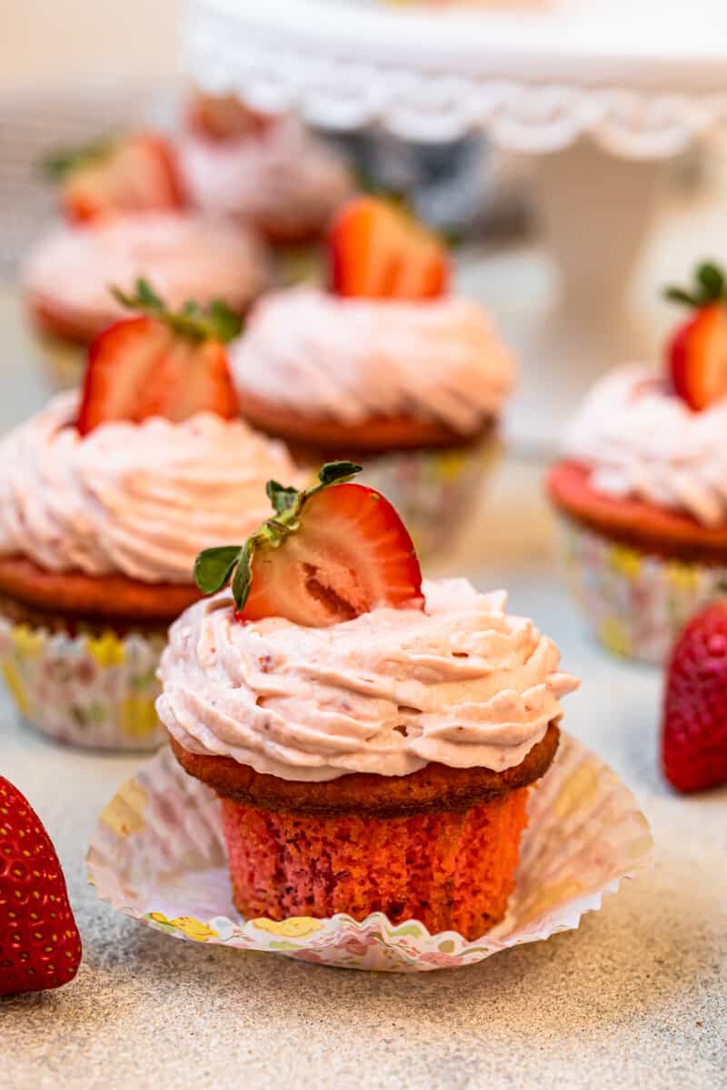 unwrapped strawberry cupcake on a colorful cupcake wrapper.