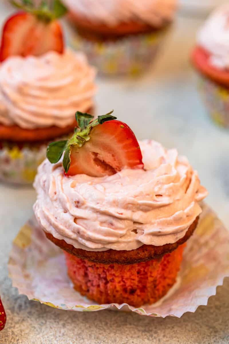 unwrapped strawberry cupcake on a colorful cupcake wrapper.