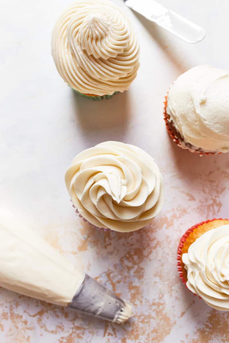 cupcakes topped with vanilla frosting in different designs