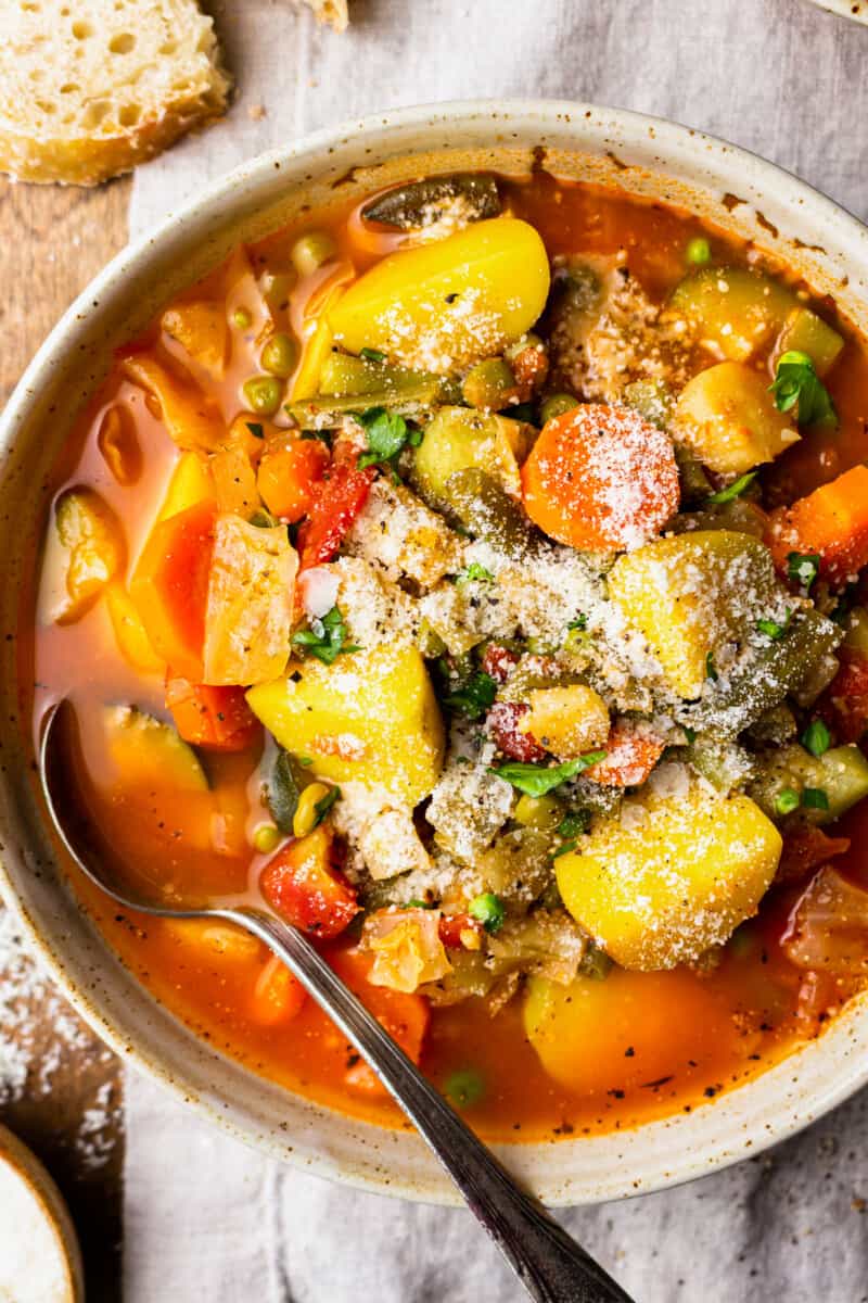 bowl of vegetable soup filled with potatoes, carrots, celery, zucchini, and more