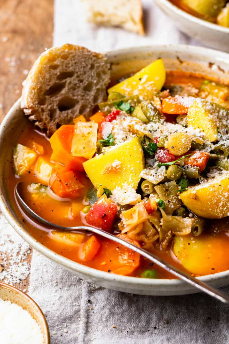a bowl of hearty vegetable soup with a piece of bread
