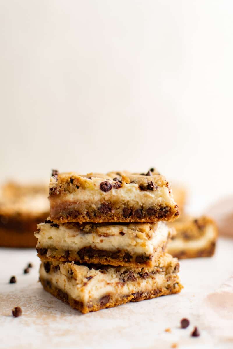 three chocolate chip cheesecake bars stacked on top of each other