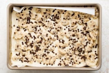 cookie dough with chocolate chips on a paper-lined baking sheet