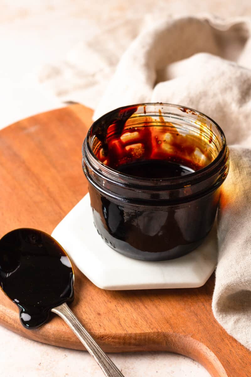 jar of balsamic reduction, with a spoon covered in the glaze next to it