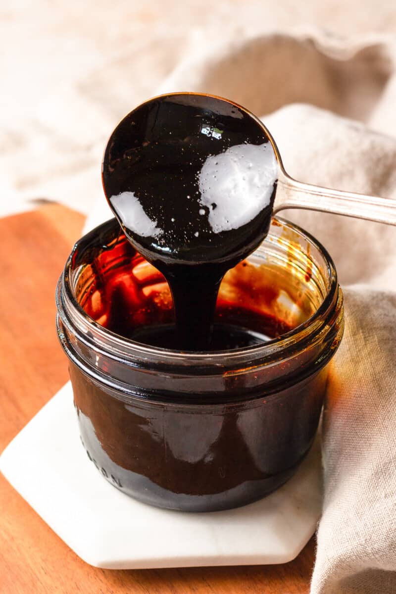 spoon dipping into a small jar of balsamic vinegar reduction