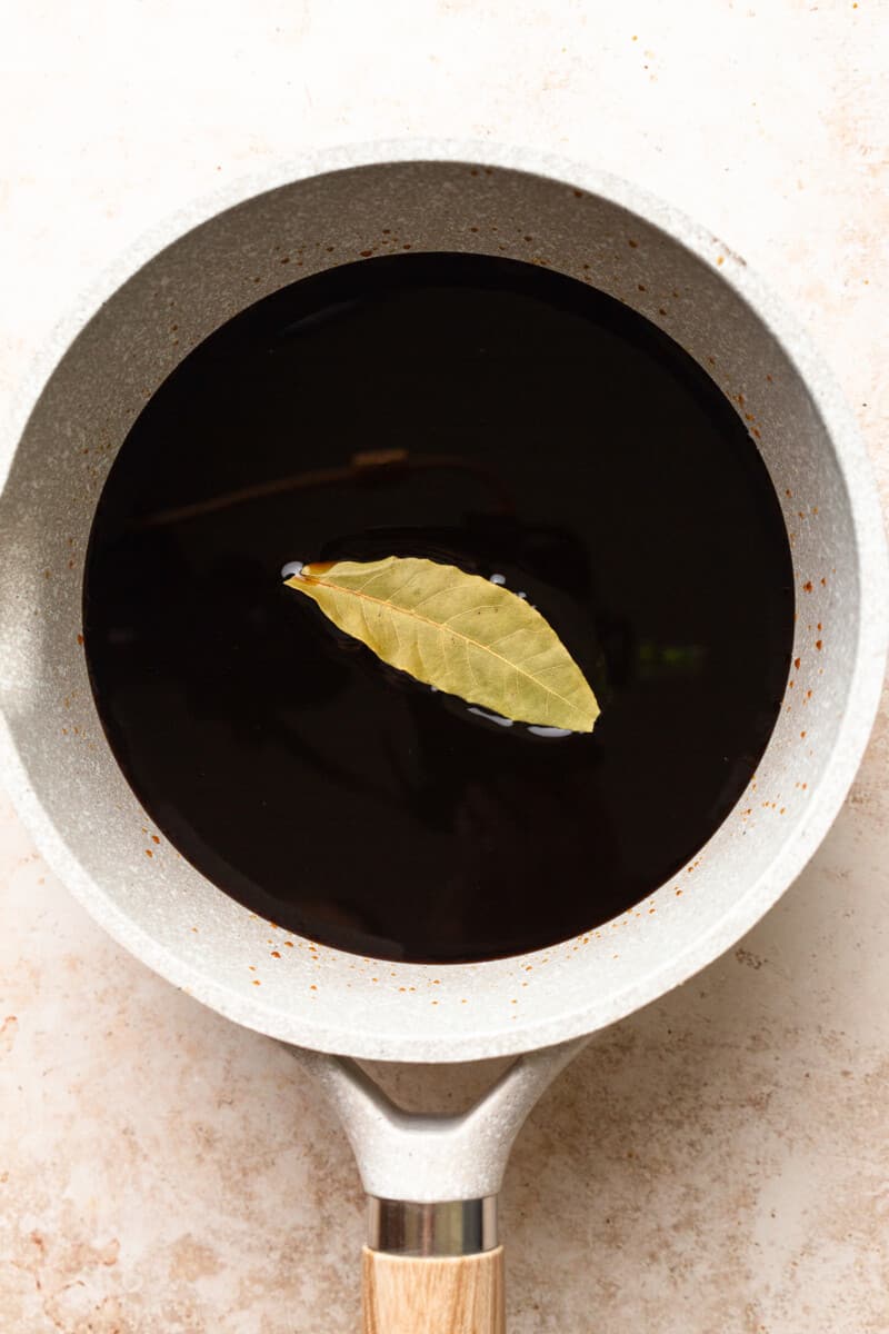 making balsamic reduction in a saucepan with a bay leaf