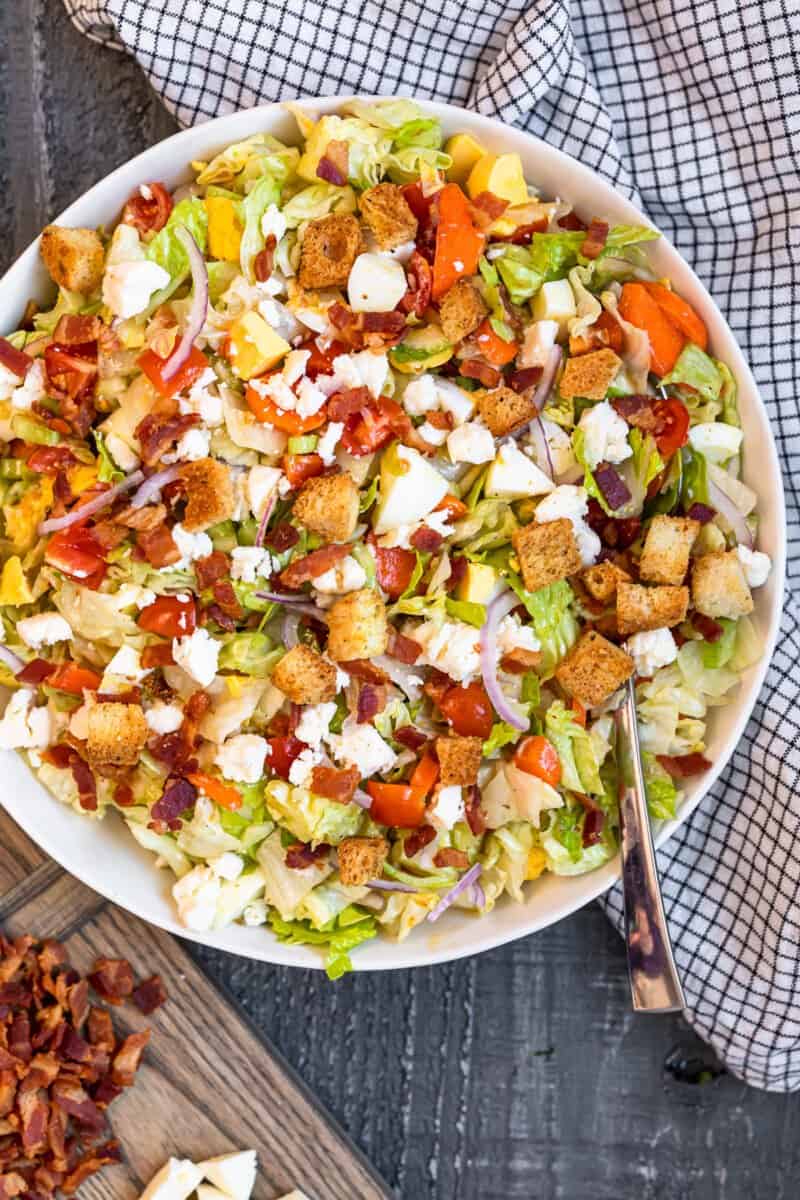 overhead view of chopped salad in a white serving bowl with a spoon.