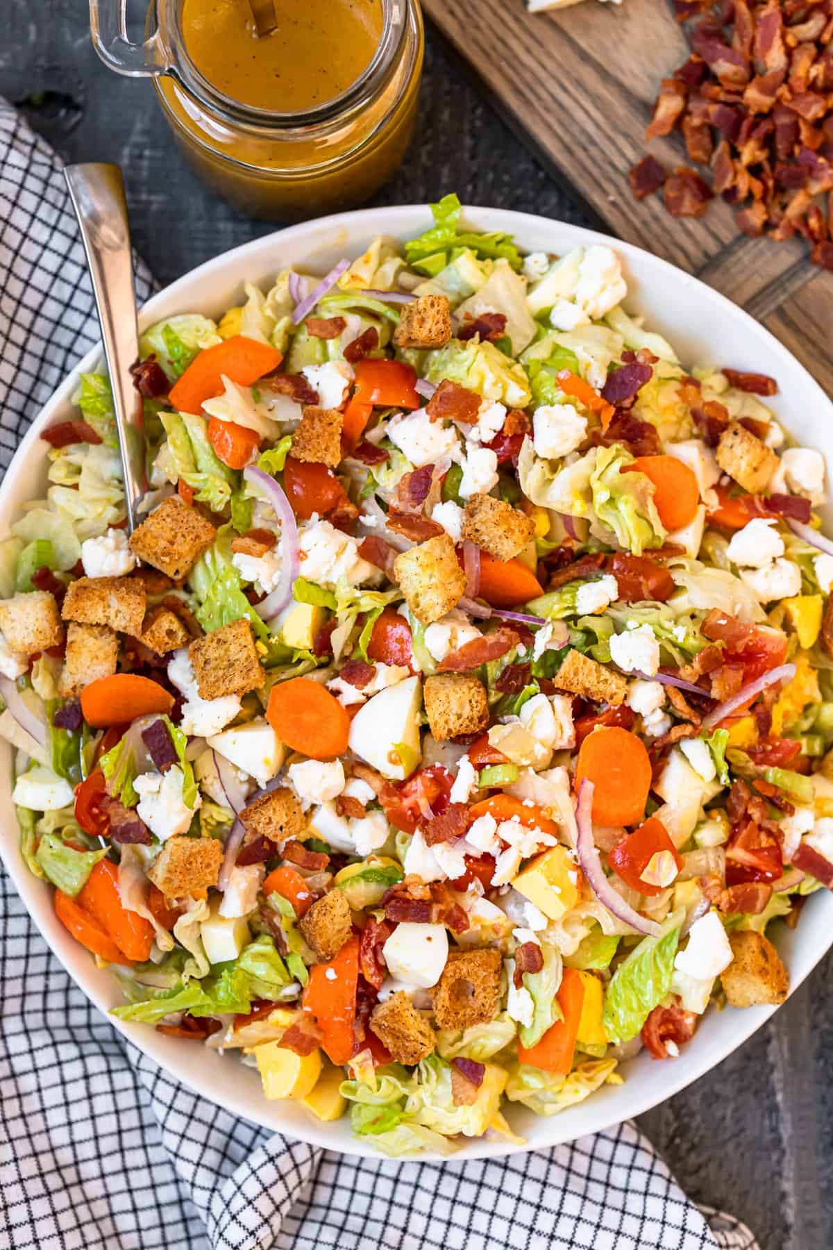 overhead view of chopped salad in a white serving bowl with a spoon.