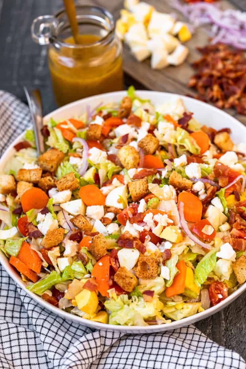 chopped salad in a white serving bowl with a spoon.