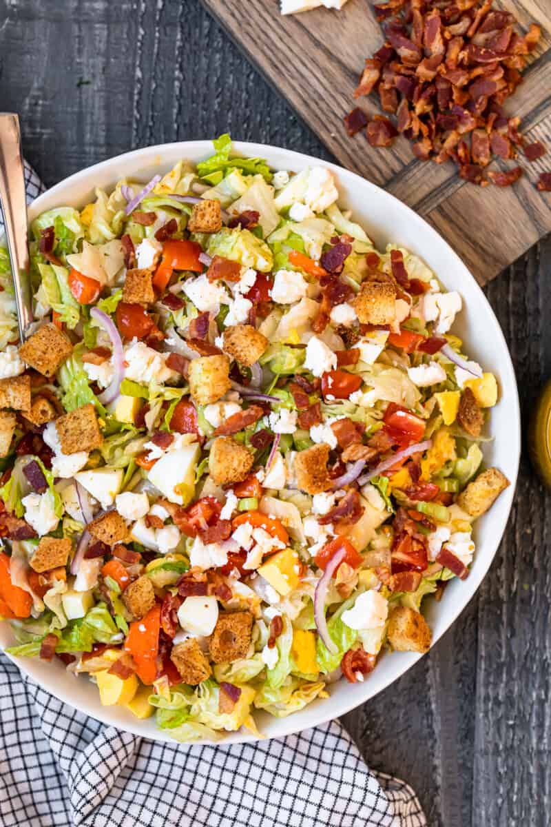 overhead view of chopped salad in a white serving bowl with a spoon.