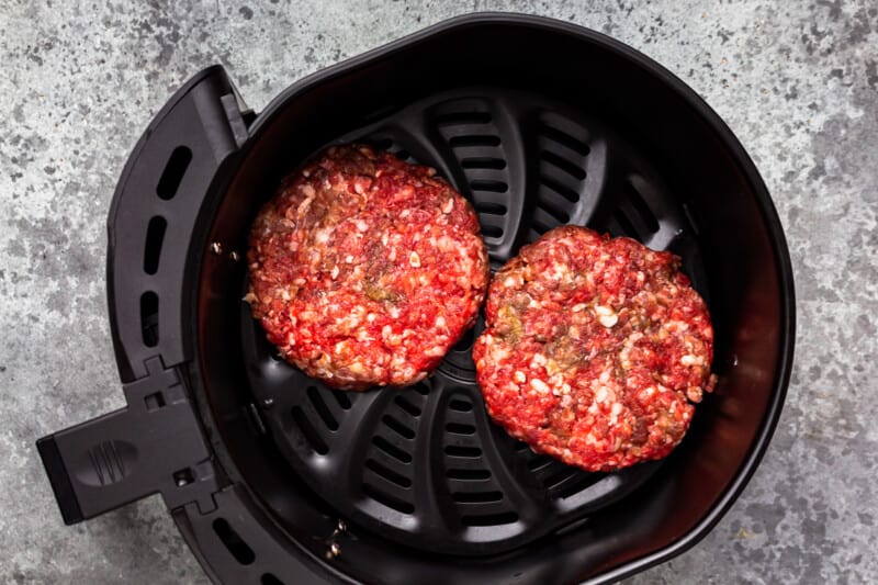 two burger patties in the basket of an air fryer