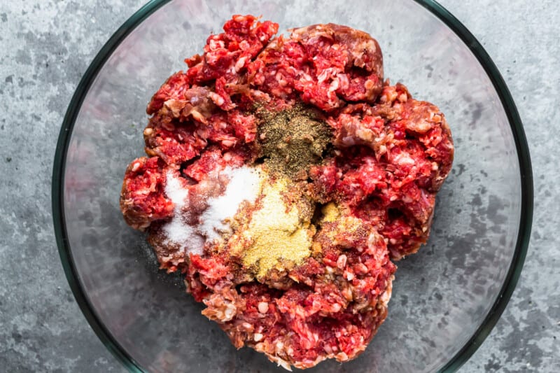 seasoning ground beef in a glass bowl