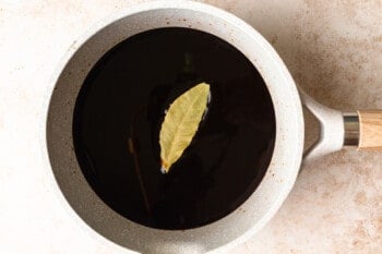 balsamic vinegar reduction in a saucepan with one bay leaf