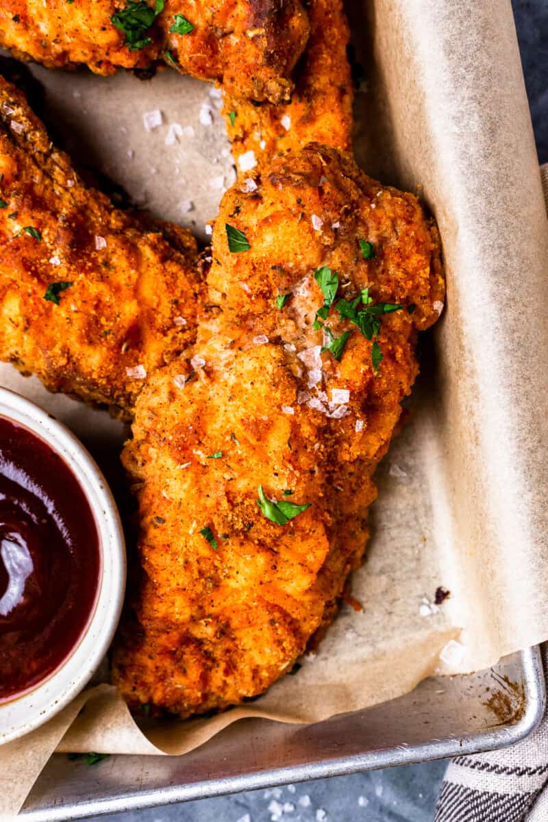 pieces of oven fried chicken on a tray with dipping sauces