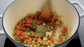mirepoix with spices and bay leaves in a dutch oven.