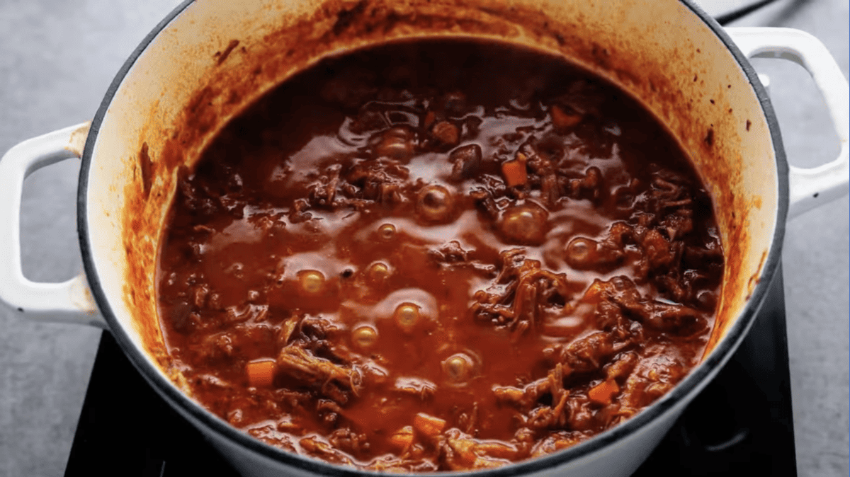 beef ragu simmering in a dutch oven.