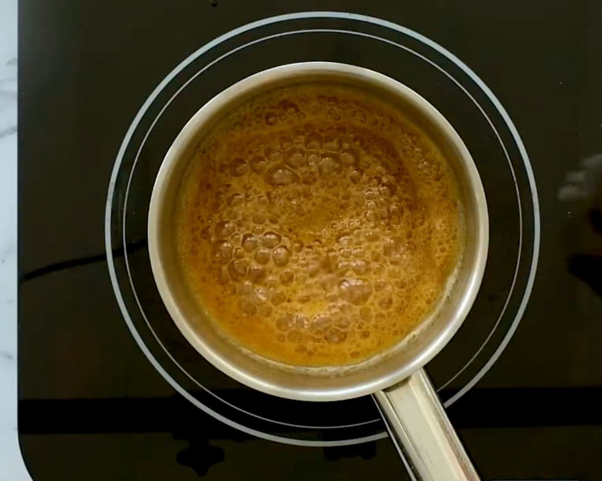 Honey simmering in a saucepan on the stovetop, starting to bubble and caramelize for balsamic glaze