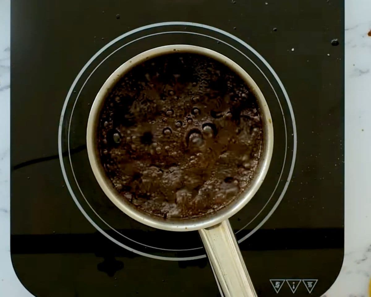 Honey balsamic glaze simmering in a saucepan, dark and bubbling as it reduces and thickens