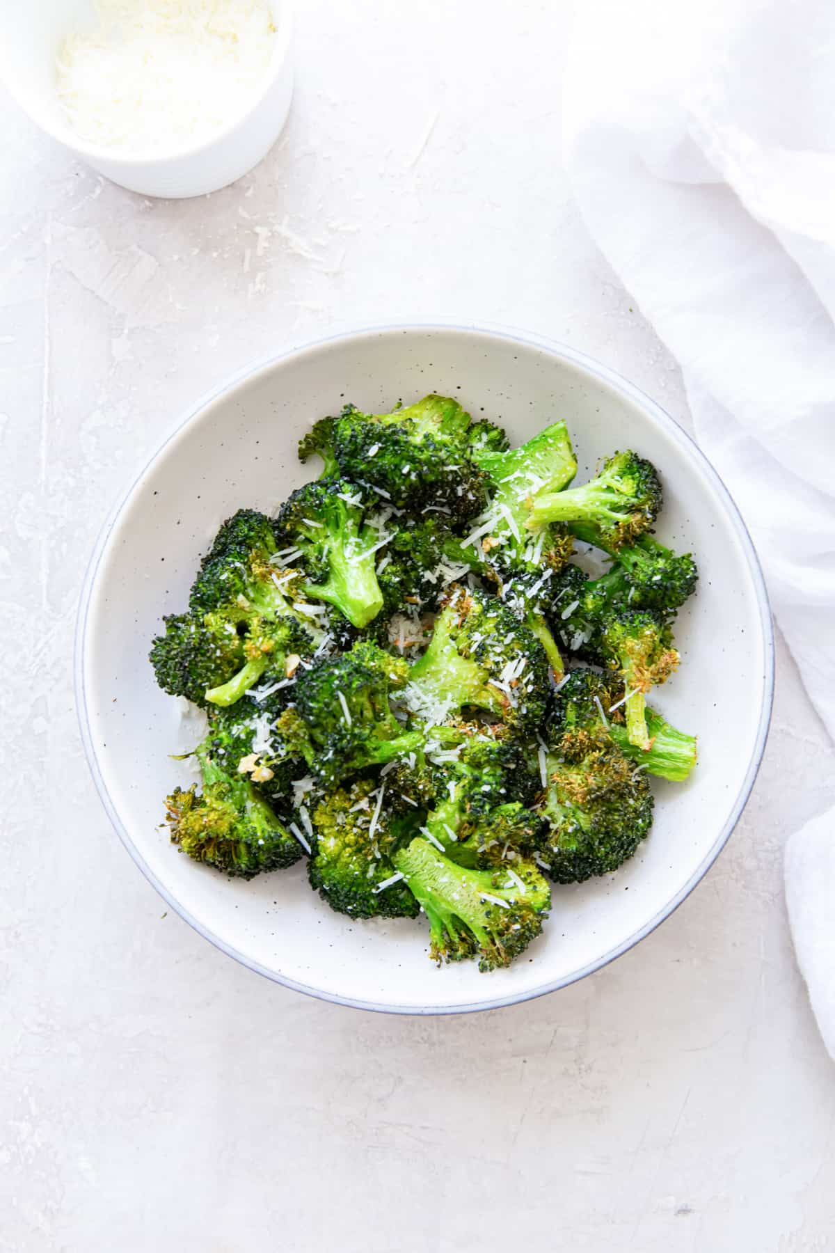 Overhead view of air fryer broccoli in a white bowl.