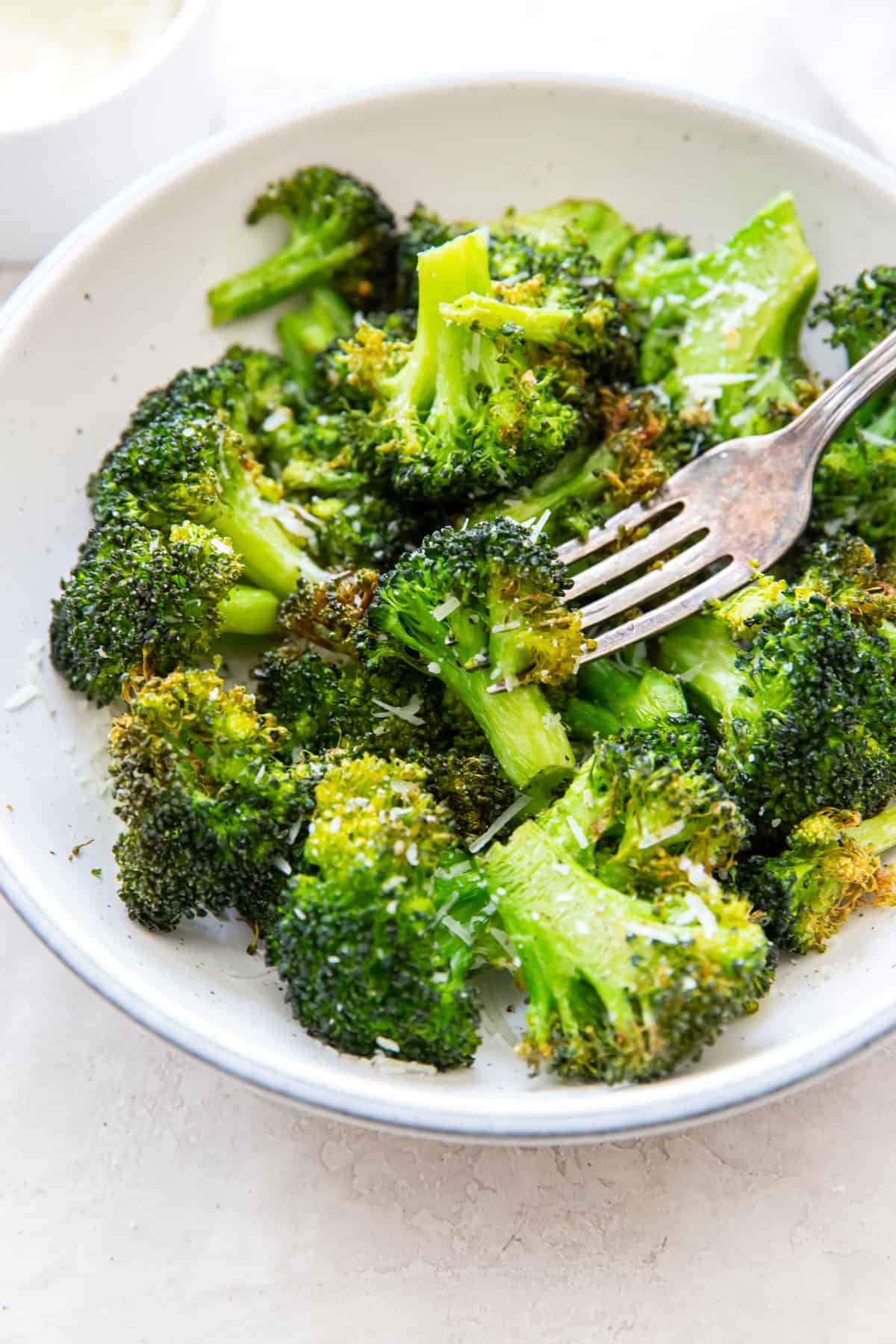 overhead view of air fryer broccoli in a white bowl with a fork.
