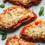 close up of 4 pieces of air fryer chicken parmesan on a white serving platter.