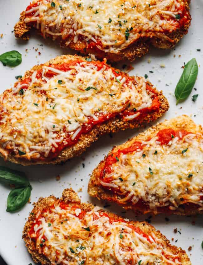 close up of 4 pieces of air fryer chicken parmesan on a white serving platter.