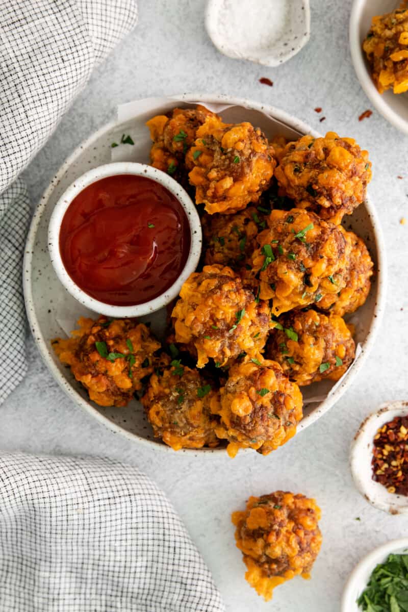 overhead view of air fryer sausage balls on a white plate with sweet chili ketchup.