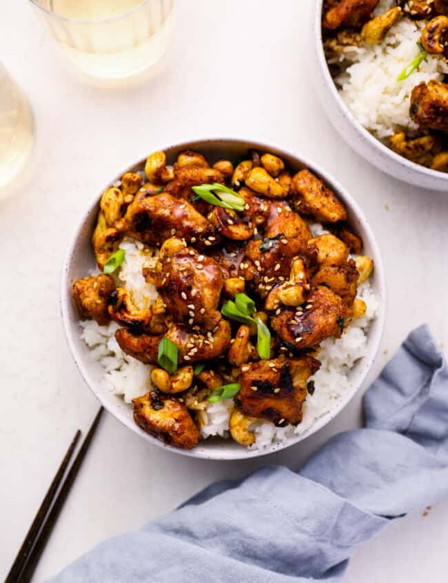 overhead view of cashew chicken in a white bowl with chopsticks.