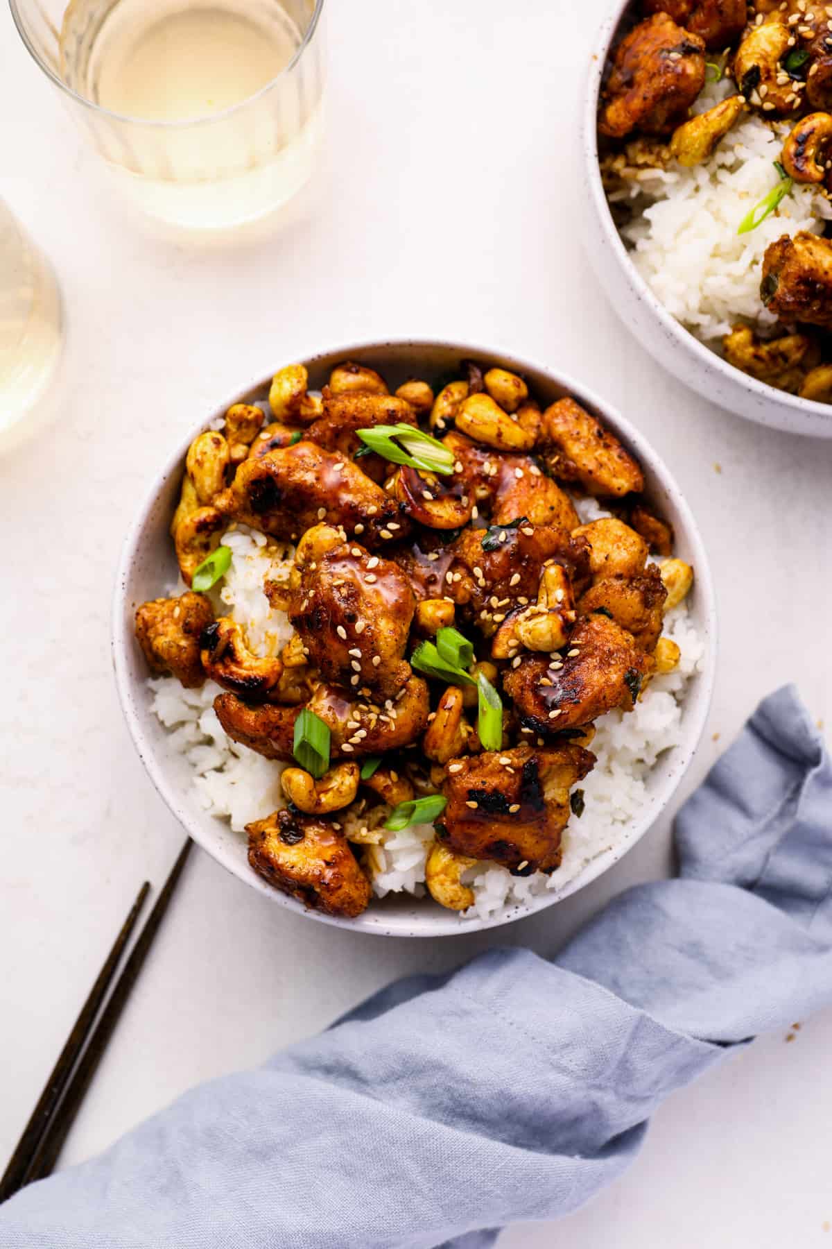 overhead view of cashew chicken in a white bowl with chopsticks.