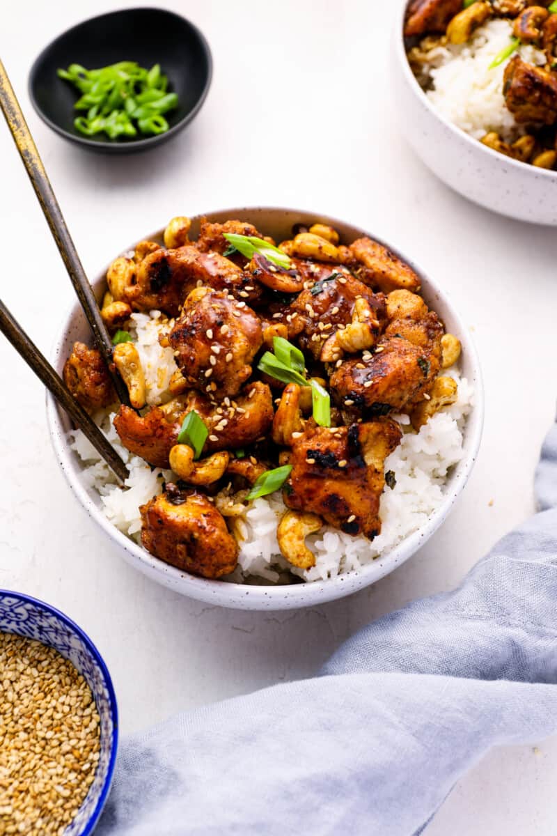 cashew chicken in a white bowl with chopsticks.