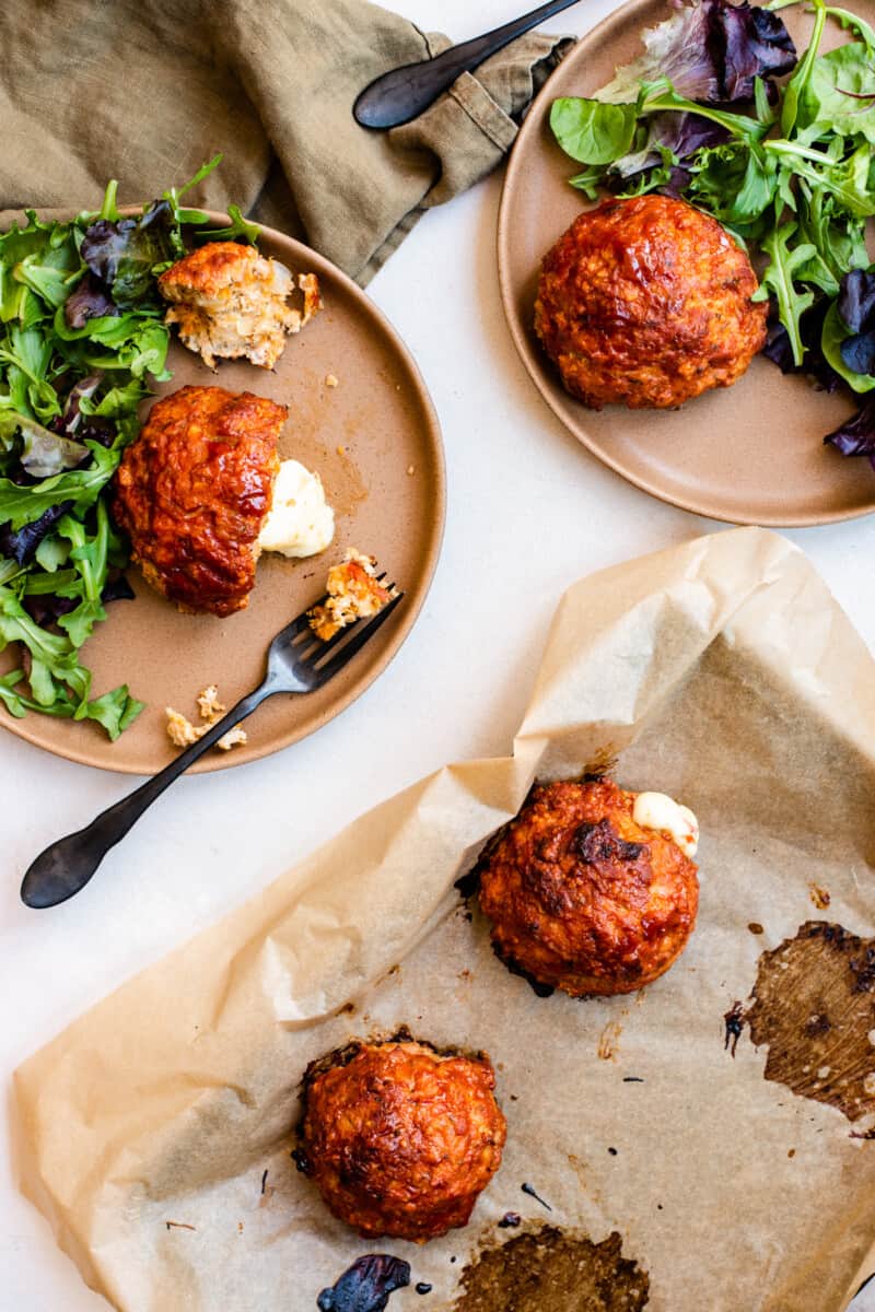 cheese-stuffed turkey meatloaves, two on a baking tray, two on separate dinner plates