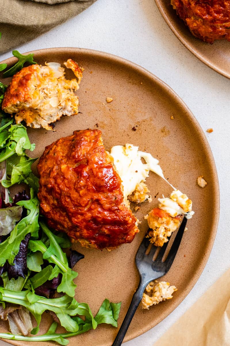 close up on a plate of food, with a mini turkey meatloaf in the center