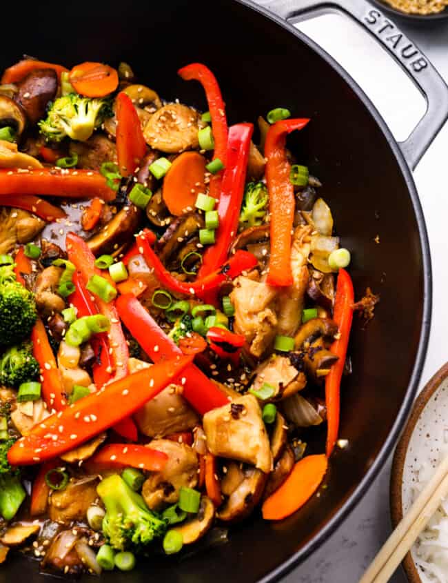 close up view of chicken stir fry in a cast iron wok.